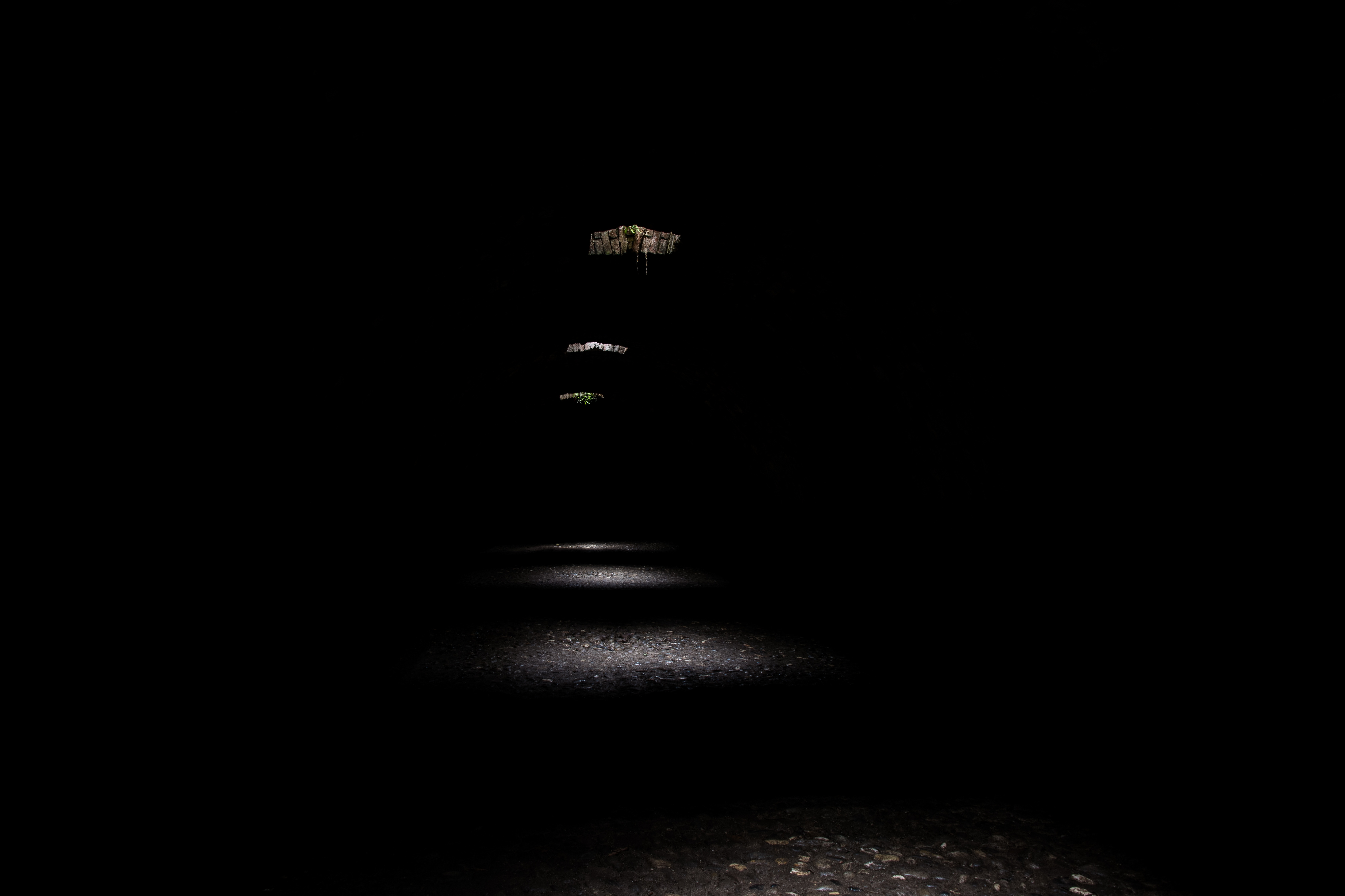 Horizontal shot of a dark tunnel with daylight entering through the holes creating mysterious image